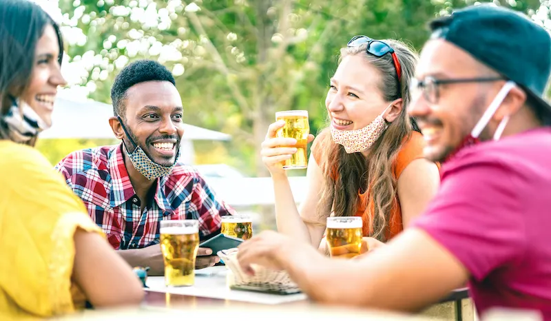 friends drinking beer with opened face masks