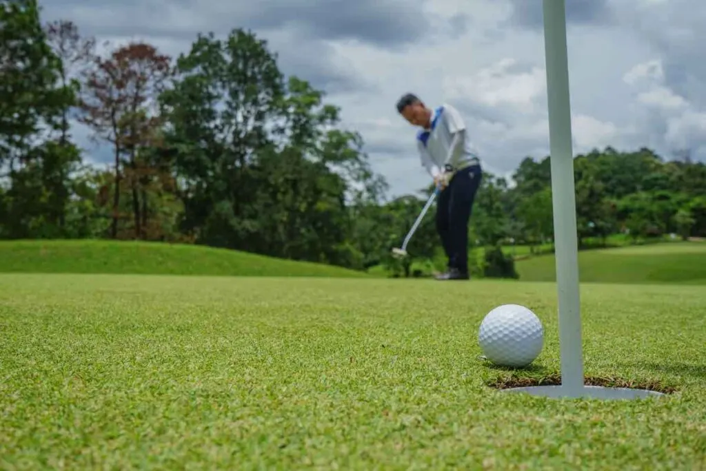 Man playing golf on a golf course in the sun