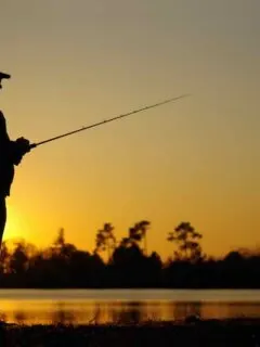 A fisherman silhouette fishing at sunset. Perhaps he's fishing at Clear Lake State Park Michigan.