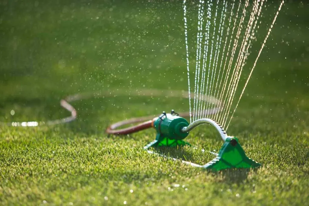 Lawn sprinkler spaying water over green grass