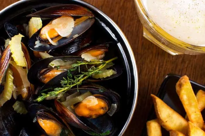 Overhead view of plate of mussels, fries, and beer.  Seafood and good beer can be found at some of the best breweries in Eugene.