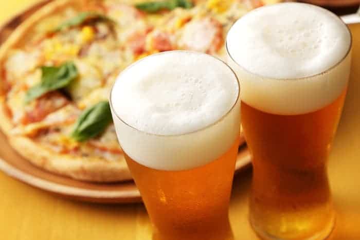 Two pint glasses of beer and an artisan pizza