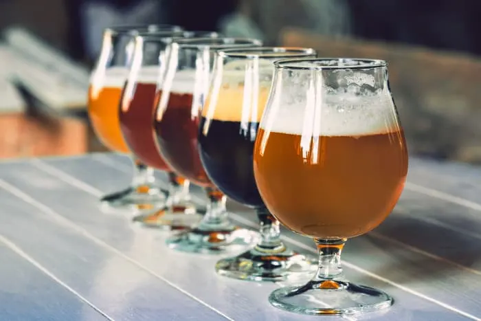 Row of glasses of craft beer on table.