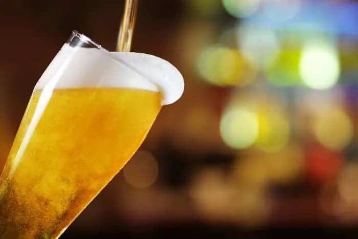 Light-colored draft beer being poured in glass.