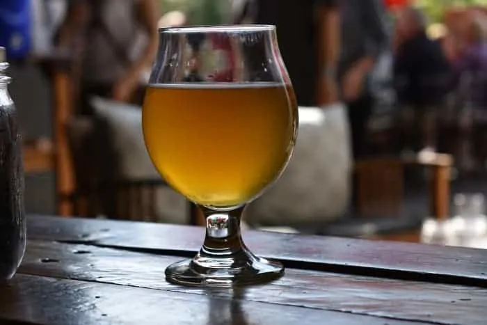 Goblet of pale colored beer on outdoor bar.