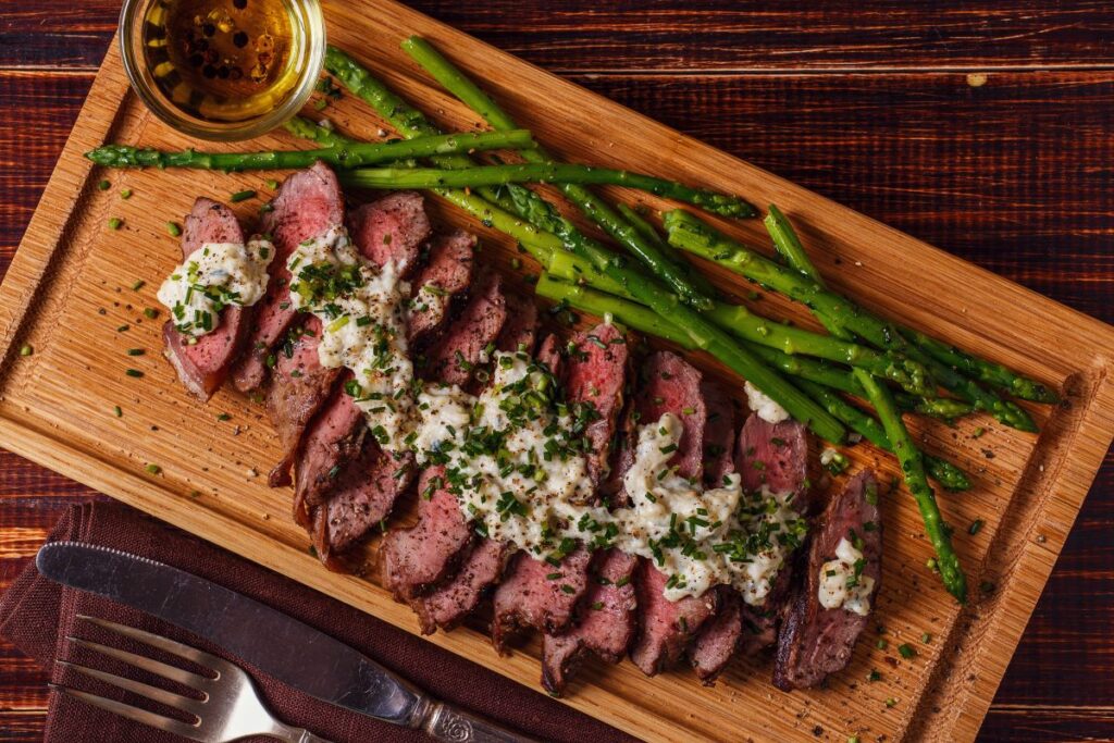 Steak and asparagus on a cutting board. Perhaps steak from the best steakhouse in Michigan.