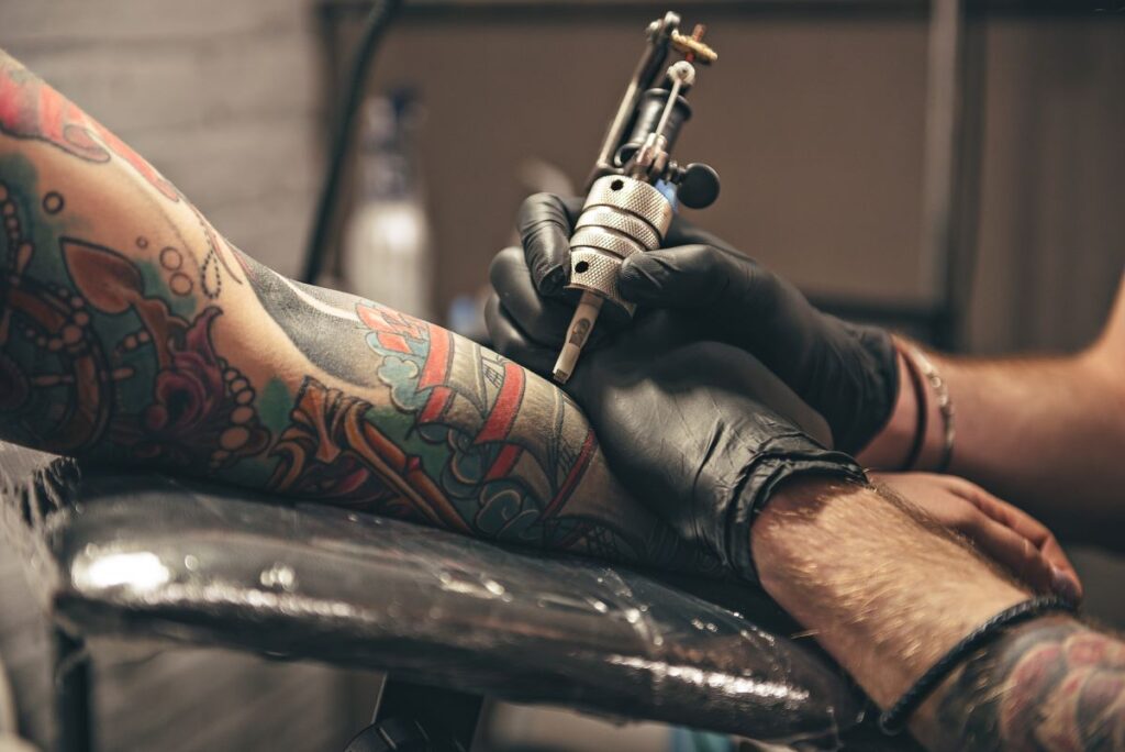 A man giving someone an arm tattoo. He's perhaps one of the best tattoo artists in Michigan.