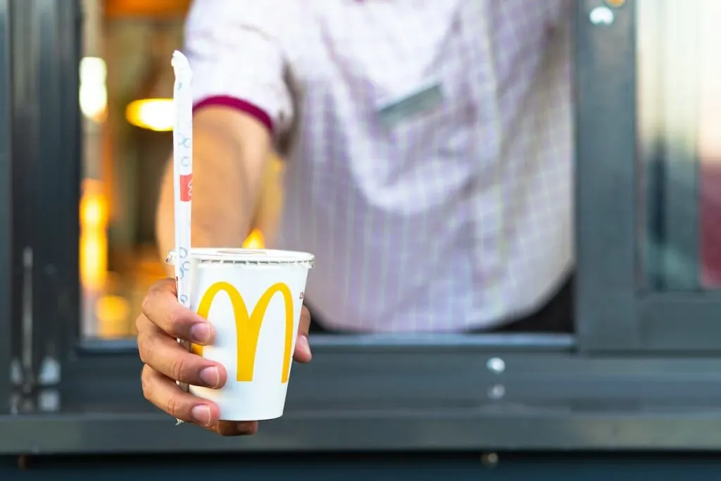 McDonald's employee handing over a drink from the drive-thru window.