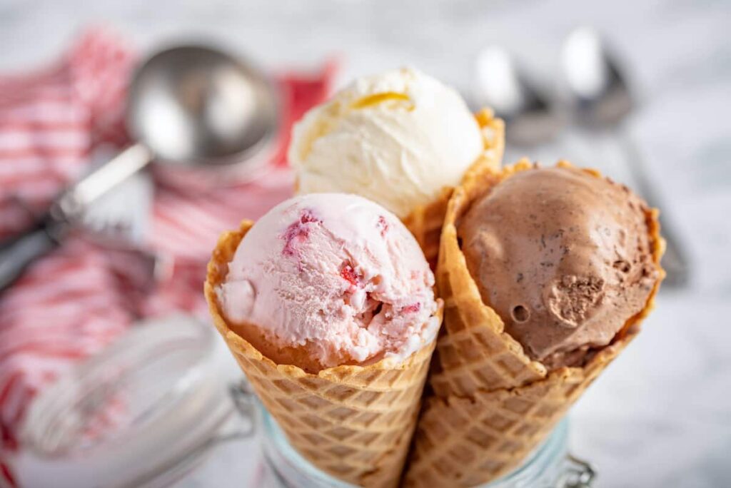 Scoops of vanilla, strawberry, and chocolate ice cream in waffle cones.